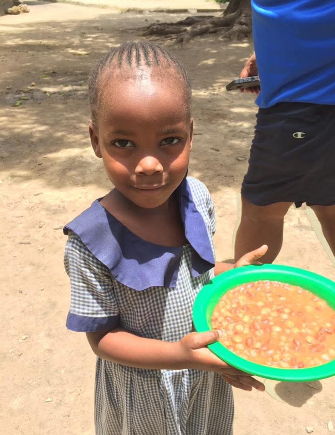 Young student in a school uniform holding a meal bowl